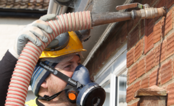 Technician installing cavity wall insulation into a brick house using specialist equipment.