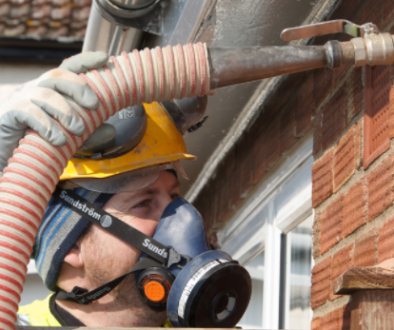 Technician installing cavity wall insulation into a brick house using specialist equipment.