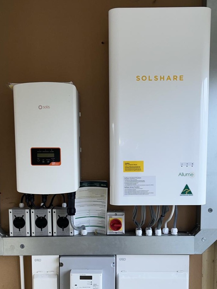 "Image of a communal solar energy system (SolShare) installed on a residential building, showcasing solar panels on the roof and energy distribution equipment designed for shared use among multiple households."